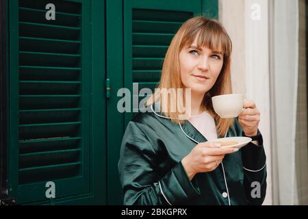Il buon giorno, la ragazza beve il caffè da una tazza bianca. Foto Stock