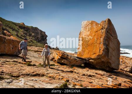 Sud Africa, Capo Occidentale, Baia di Plettenberg, Riserva Naturale di Robberg, Capo Seal, due turisti che camminano su un sentiero roccioso sopra la costa, accanto al mare pesante Foto Stock