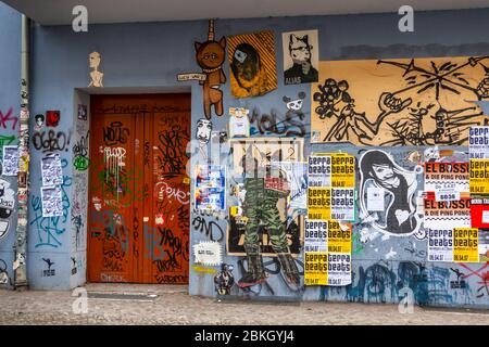 Una porta arancione è coperta da cima a fondo di poster di concerti, figure di graffiti e adesivi; diversi poster pubblicizzano la serie di feste ‚Terra Beats‘. Boxhagener Straße, Boxhagener Kiez, Friedrichshain, Friedrichshain-Kreuzberg, Berlino, 10245, Germania Foto Stock