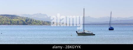 Due barche a vela al Lago Ammer (Ammersee). In lontananza le alpi europee con la montagna più alta della Germania, le Zugspitze. Formato panorama. Foto Stock