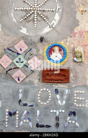 Particolare di un'installazione artistica sulla parete di un edificio nel villaggio di Marsaxlokk, Malta. I materiali intarsiati includono gusci e piastrelle. Foto Stock