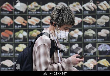 Tokyo, Giappone. 4 maggio 2020. Un uomo che indossa la maschera passa da un ristorante sushi a Tokyo, Giappone, 4 maggio 2020. Il governo giapponese ha ufficialmente annunciato lunedì la sua decisione di prorogare di quasi un mese lo stato di emergenza nazionale per il COVID-19 fino al maggio 31. Credit: Yuyuyu/Yuyu Live News Foto Stock