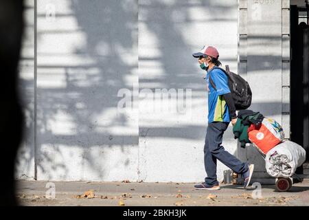 Persone reali preoccupate, protette con maschere e a piedi che trasportano borse di shopping nelle strade di Providencia durante la malattia di infezione da coronavirus COVID-19 Foto Stock