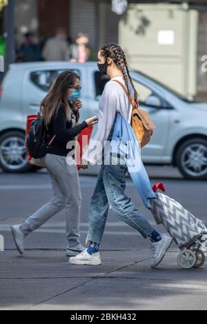 Persone reali preoccupate, protette con maschere e a piedi che trasportano borse di shopping nelle strade di Providencia durante la malattia di infezione da coronavirus COVID-19 Foto Stock