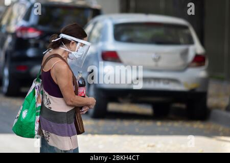 Persone reali preoccupate, protette con maschere e a piedi che trasportano borse di shopping nelle strade di Providencia durante la malattia di infezione da coronavirus COVID-19 Foto Stock