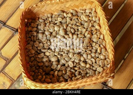 Accappatoio di vimini a strisce di bambù ripieno di chicchi di caffè arabica freschi. Primo piano del processo naturale di essiccazione dei chicchi di caffè presso la fabbrica di caffè di Bali Foto Stock