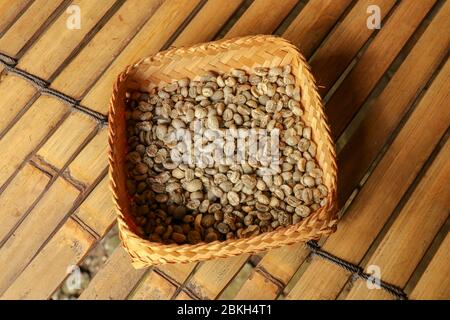 Accappatoio di vimini a strisce di bambù ripieno di chicchi di caffè arabica freschi. Primo piano del processo naturale di essiccazione dei chicchi di caffè presso la fabbrica di caffè di Bali Foto Stock