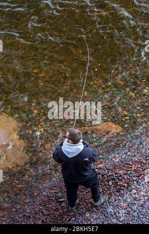 Fisherman che atterra una grande trota fuori dal lago Superior nel Tettegouche state Park lungo la costa settentrionale del Minnesota, USA {Nessun modello di rilascio; disponibile per Foto Stock