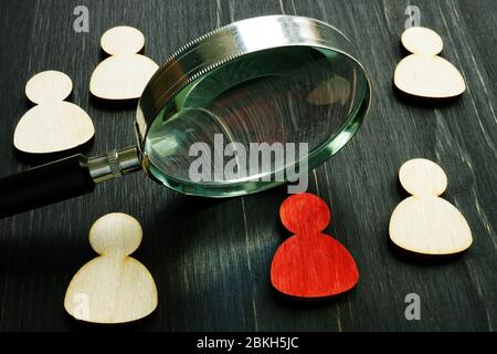 Acquisizione di talenti. Lente d'ingrandimento e figure in legno come simbolo di un dipendente. Foto Stock