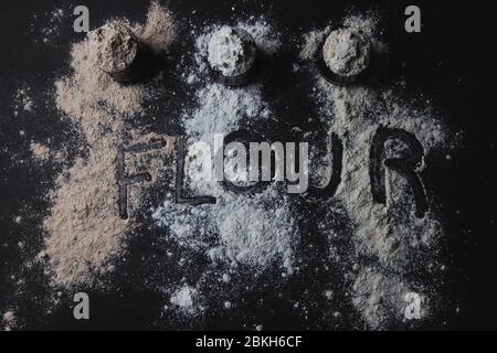 Tre vasetti pieni di diversi tipi di farina, alternative senza glutine, farina cosparta e la parola farina scritta sopra Foto Stock