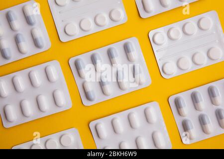 pacchetti di pillole e compresse per farmaci su sfondo giallo brillante Foto Stock