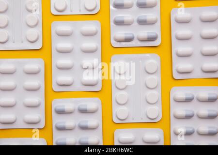 pacchetti di pillole e compresse per farmaci su sfondo giallo brillante Foto Stock