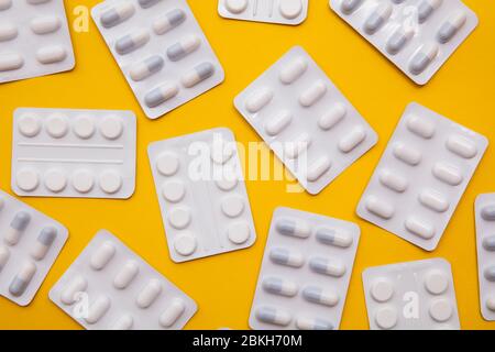 pacchetti di pillole e compresse per farmaci su sfondo giallo brillante Foto Stock