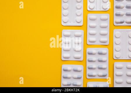 pacchetti di pillole e compresse per farmaci su sfondo giallo brillante Foto Stock