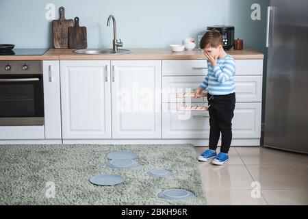 Ragazzino scioccato con piatti caduti a casa Foto Stock