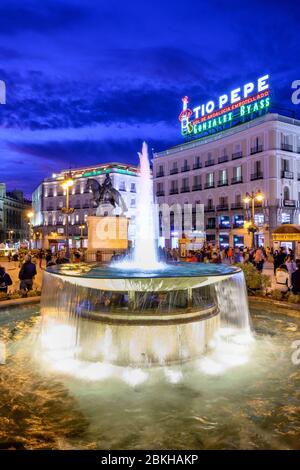 Il famoso Tio Pepe pubblicità segno telai su una statua di re Carlos III, la Puerta del Sol di Madrid, Spagna. Foto Stock