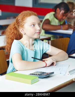 Una scolaretta attenta si siede in classe in una scuola elementare Foto Stock