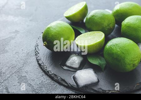 Lime fresche e cubetti di ghiaccio su sfondo scuro Foto Stock