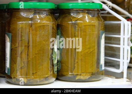 Vasi di varie verdure sottaceto venduti in magazzino. Foglie di uva in scatola. Ingrediente per cucinare dolma. Foto Stock