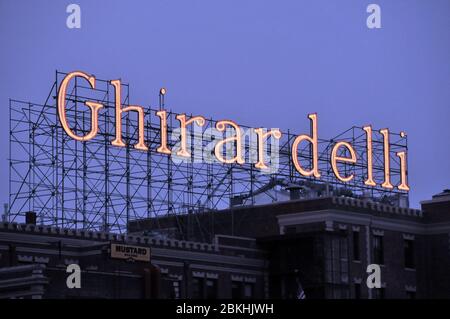 Ghirardelli illuminato segno sopra gli edifici di Fishermans Wharf, San Francisco, California, USA come la notte cade Foto Stock