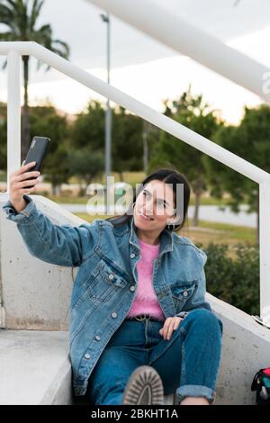 Giovane donna fa un selfie in un campus universitario Foto Stock