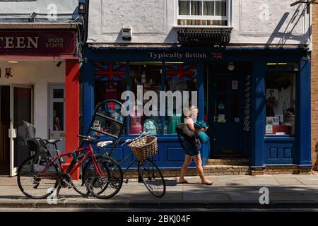 donna cammina davanti a un negozio di articoli da regalo e parcheggia le biciclette Le strade di Cambridge Foto Stock