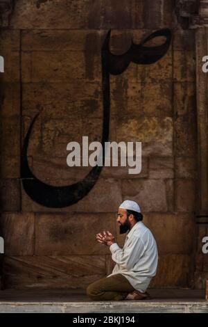 India, Gujarat state, Ahmedabad, Jami Masjid, Grande Moschea, uomo musulmano che prega di fronte alla calligrafia arabica Foto Stock