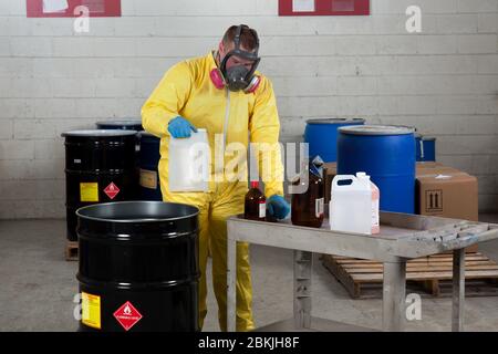 Un lavoratore in abito da nocciola dispone di sostanze chimiche pericolose Foto Stock