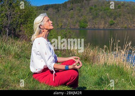 Europa, Lussemburgo, Insenborn, attraente donna anziana meditata da Lac Sûre Foto Stock