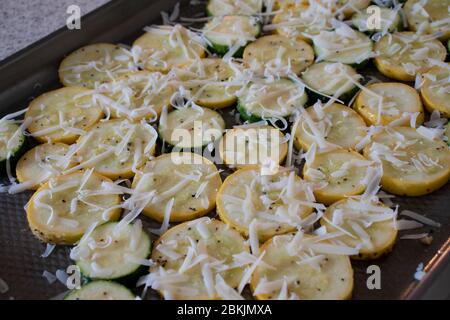 Un contorno di zucca gialla a fette e zucchine arrostite al forno e ricoperte di parmigiano. Foto Stock