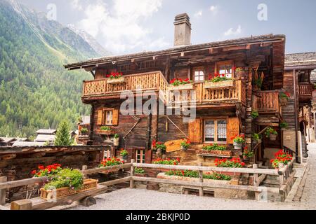 Bella casa in legno decorata con gerani sui balconi nel pittoresco villaggio alpino svizzero Grimentz, comune di Anniviers, cantone di va Foto Stock