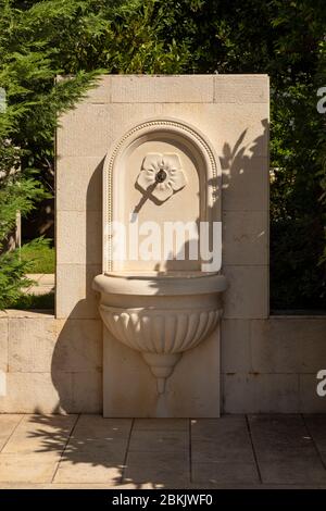 Una piccola fontana pubblica per bere a Bol, isola di Brac in Dalmazia, Croazia. Stile Romano con pietra di colore bianco. Un dettaglio floreale scolpito Foto Stock