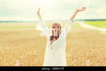 Sorridente giovane donna in abito bianco sul campo di cereali Foto Stock