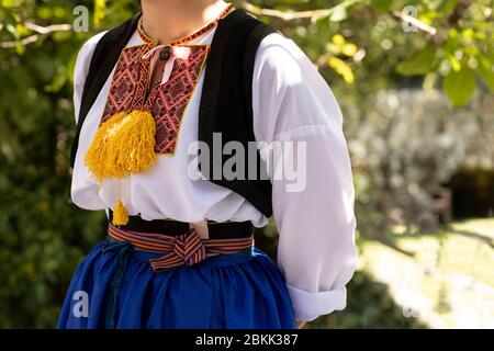 Un dettaglio di un tradizionale costume croato dalmata di Cilipi, Dubrovnik. Una ragazza che indossa un abito in stile folklore con ricami colorati su un sole Foto Stock