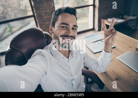 Autoritratto del suo lui bello attraente classe fiducioso allegro uomo barbarare economista consulente avvocato mostrando v-segno al loft moderno Foto Stock