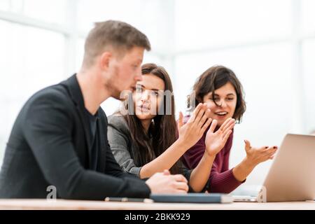 giovani che discutono di qualcosa che siede al tavolo Foto Stock