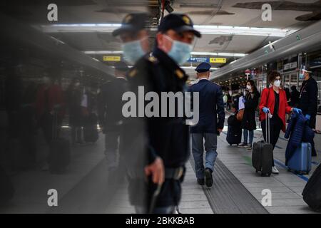 Gli agenti di polizia controllano i passeggeri che indossano maschere protettive dopo l'arrivo con un treno ad alta velocità Frecciarossa nella stazione centrale di Napoli, nel sud Italia. I passeggeri si sono staccati ordinatamente e hanno seguito il percorso indicato dalla polizia, allineando per far controllare le temperature del corpo sulla piattaforma della stazione. Il governo italiano gradualmente aboliva le restrizioni di blocco che furono attuate per arginare la diffusione del coronavirus che ha causato la malattia di Covid-19. Foto Stock