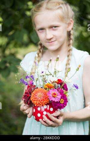 Ragazza con un bellissimo luminoso bouquet di fiori selvatici nelle sue mani Foto Stock