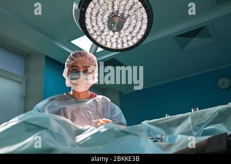 Close up ritratto di giovane donna medico chirurgo di indossare la maschera protettiva e hat durante l'operazione. La sanità, l'istruzione medica, concetto di chirurgia Foto Stock