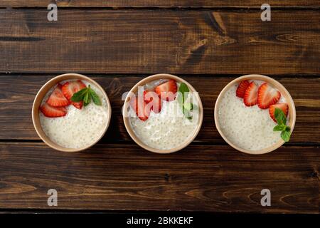 Tre tazze di carta artigianale con budino di tapioca con latte a base di piante. Vista dall'alto Foto Stock