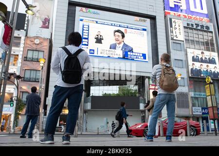 Tokyo, Giappone. 4 maggio 2020. La gente guarda un grande schermo che mostra una trasmissione in diretta del primo Ministro giapponese Shinzo Abe parla a una conferenza stampa a Tokyo, Giappone, il 4 maggio 2020. Il Giappone estende lo stato di emergenza a livello nazionale fino alla fine del mese per frenare la diffusione del romanzo coronavirus. Credit: AFLO/Alamy Live News Foto Stock