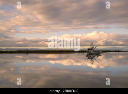 Pesca al mare Steveston Harbor Twilight. Una barca sulla senna viaggia fuori dall'entrata del porto di Steveston nello stretto di Georgia. Le nuvole di tempesta si profilano nella b Foto Stock