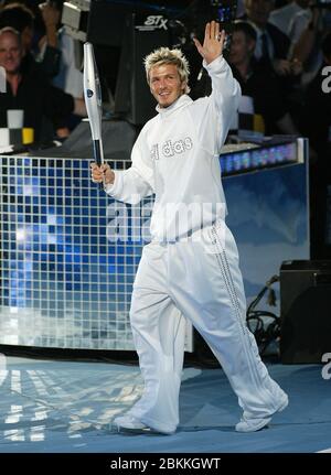 MANCHESTER - LUGLIO 25: Il giocatore di calcio britannico David Beckham che tiene la Jubilee Baton corre nello stadio del City of Manchester Stadium durante il 2002 Foto Stock