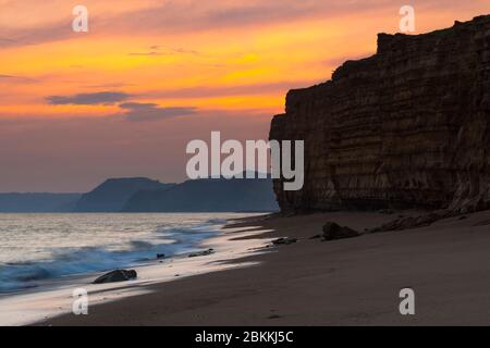 Burton Bradstock, Dorset, Regno Unito. 4 maggio 2020. Meteo Regno Unito. Le nuvole si illuminano di arancione al tramonto a Hive Beach a Burton Bradstock nel Dorset guardando verso ovest verso Golden Cap mentre la nuvola si sviluppa prima della pioggia prevista. Credito immagine: Graham Hunt/Alamy Live News Foto Stock