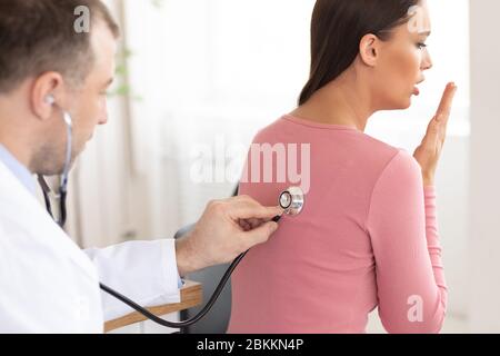Medico esperto che controlla il respiro di una paziente femmina Foto Stock