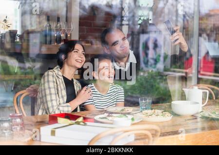 Una famiglia felice di tre selfie in un caffè. Foto Stock