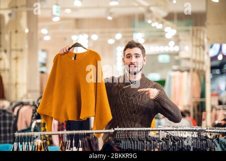 Un adolescente che aiuta la sua ragazza a trovare il maglione giusto in un negozio di abbigliamento. Foto Stock