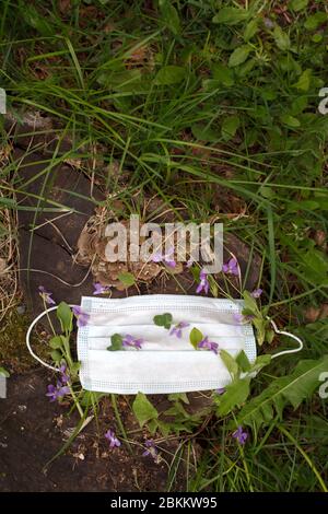 Maschera protettiva blu decorata con fiori primaverili, isolamento a casa per la quarantena. Concept home quarantena, prevenzione COVID-19, Coronavi Foto Stock