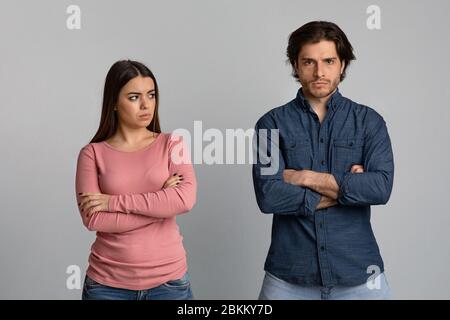 Giovane asiatico che guarda con dolore alla sua ragazza arrabbiata, coppia lotta su sfondo grigio Foto Stock