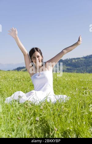 Junge glueckliche Frau streckt ihre Haende in den Himmel, MR: Sì Foto Stock